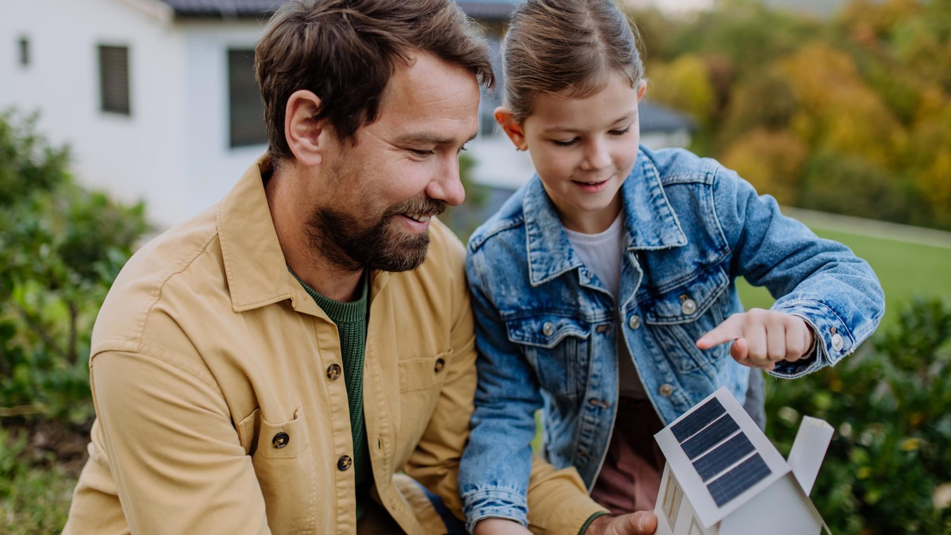 Far og datter lærer om solenergi med et papirmøllehus